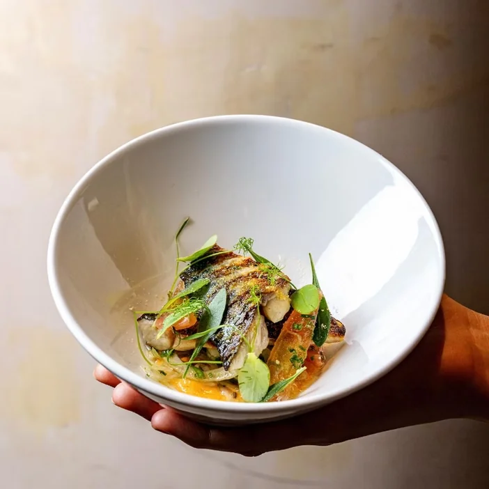 A white bowl of food held ready for service