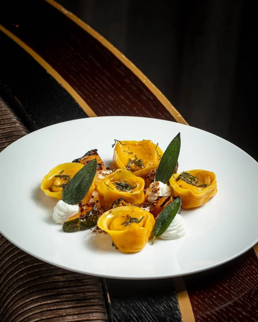 Yellow filled pasta with green leaves on a white plate