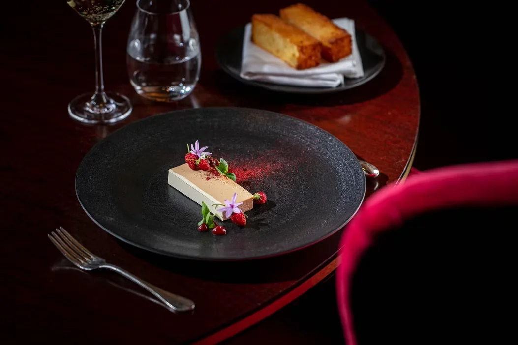 A plated course on a dining table with glasses and brioche